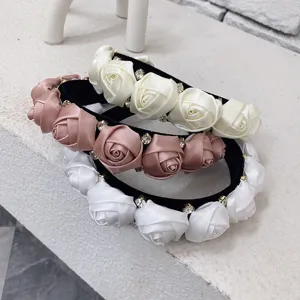 Detailed macro view of three 3D satin rose flower headbands with sparkling rhinestones.