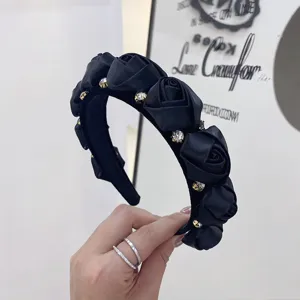 Detail of black wide-brim headband featuring 3D roses and sparkling rhinestones