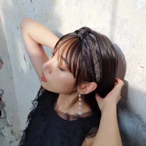 Elegante diadema de tela negra con adornos de pedrería brillante en una modelo