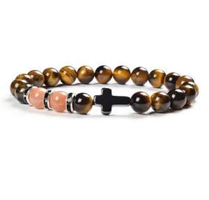 Detailed close-up view of beaded bracelet featuring tiger eye stones and a black cross charm.