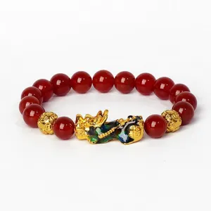 Gros plan détaillé des perles en agate rouge et du pendentif Pixiu doré sur le bracelet.