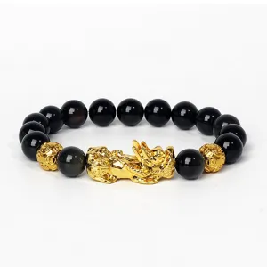 Gros plan sur le bracelet de perles noires avec un charm Pixiu doré et perles monnaie.