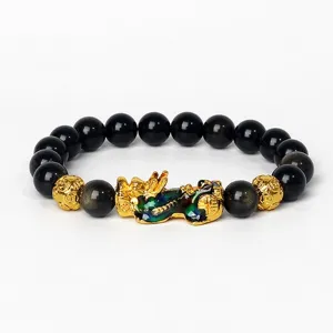 Détail de bracelet en perles d'obsidienne avec charm Pi Xiu doré et perles de pierre noire.