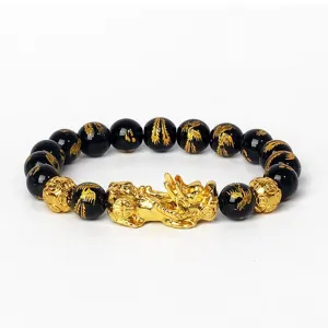 Détail de bracelet en perles noires avec charm Pixiu doré et motifs sculptés élégants.