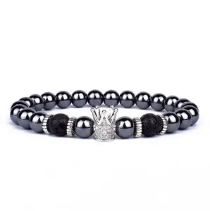 Detailopname van de kralenarmband met zilveren kroonbedel en zwarte lavasteen kralen.
