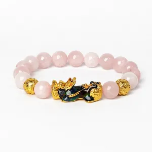 Détail de bracelet Pixiu en quartz rose et or, doté d'un design extensible élastique chic.