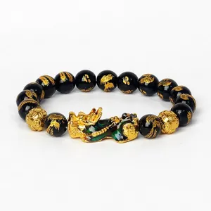 Vue détaillée du bracelet en perles noires et pendentif Pixiu doré, bijou au design traditionnel.