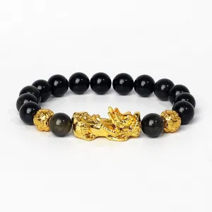 Gros plan détaillé du bracelet de perles noires avec un charm Pixiu doré et des perles d'accent.