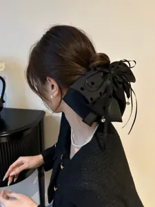 Gros plan sur une pince à cheveux nœud noir à pois géant sur un chignon bas élégant