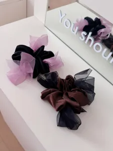 Detail van elegante satijnen haarelastiekjes met gaasstrikken op een wit oppervlak.