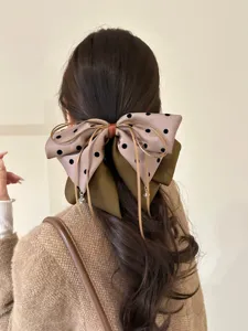 Vue détaillée d'une pince à cheveux à gros nœud marron à pois pour des coiffures chic