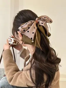 Grande pince à cheveux avec nœud à pois et longs rubans, vue arrière sur cheveux ondulés.