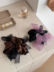Elegante satijnen en mesh bow scrunchies in bruin en zwart op een tegelachtergrond.