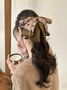 Vue détaillée d'une grande pince à cheveux avec nœud à pois sur cheveux ondulés