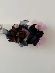 Detailweergave van bruine en zwarte satijnen haarelastiekjes met organza strikken
