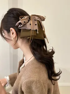 Vue détaillée d'une grande pince à cheveux élégante avec un nœud à pois au style rétro.