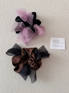 Detailweergave van twee satijnen scrunchies met transparante mesh linten in paars en zwart