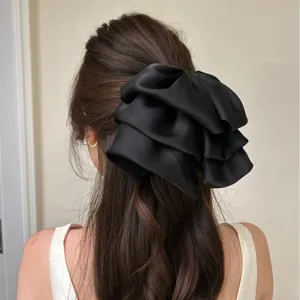 Vue détaillée d'une grande pince à cheveux avec un nœud en satin noir multicouche sur modèle.
