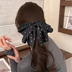 Détail d'une grande pince à cheveux nœud à pois noirs sur une queue de cheval