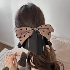 Gros plan d'une grande pince à cheveux avec nœud à pois et garniture de strass