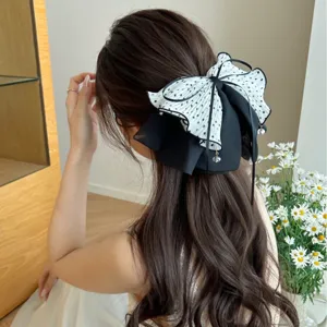 Détail d'une grande pince à cheveux à nœud à pois sur de longs cheveux bruns ondulés