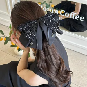 Détail rapproché d'une grande pince à cheveux élégante avec un nœud à pois noirs
