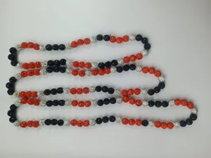 Detailed view of 10mm black, orange, and silver rhinestone clay beads on an elastic cord.