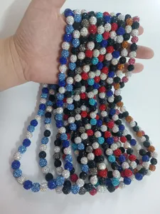 Hand holding multiple strands of 10mm colorful rhinestone clay beads for jewelry making
