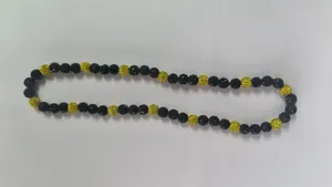 Detailed view of black and yellow Shamballa disco ball bead necklace on white surface.