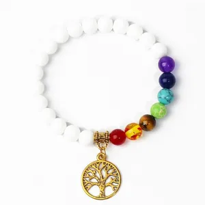 Close-up detail of a white chakra beaded yoga bracelet featuring a gold tree of life charm.