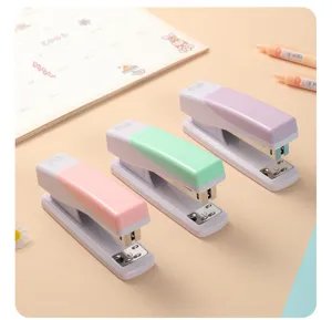Cucitrici da scrivania pastello in rosa, verde e viola esposte su una scrivania pulita.