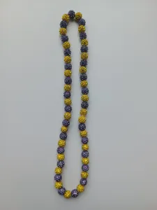 Close-up detail of purple and yellow 10mm rhinestone bead shamballa necklace on white