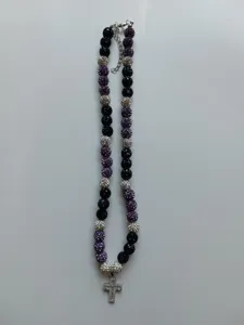 Close-up of beaded necklace with black purple silver rhinestone shamballa beads and a cross pendant.