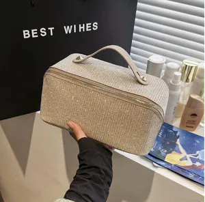 Detailansicht der schimmernden goldfarbenen Glitzer-Textur einer großen Kosmetiktasche