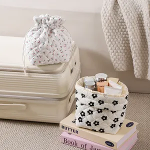 Quilted floral cosmetic bags with drawstring closure placed on books and suitcase
