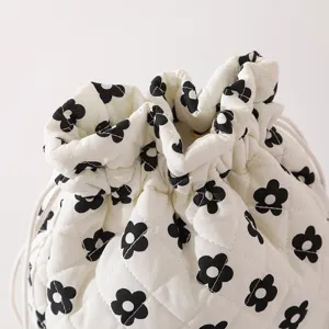 Detailed close-up of a white quilted drawstring makeup bag with black floral patterns