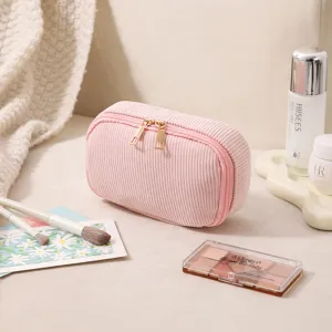Detail einer weichen rosa Cord-Kosmetiktasche mit eleganten Doppel-Goldreißverschlüssen