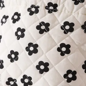 Close-up detail of quilted white fabric with black floral pattern on storage bag