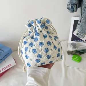 Macro detail of white quilted cotton drawstring storage bag with blue rose patterns.