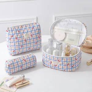 Detail view of quilted cotton cosmetic bag set featuring cherry prints and blue grid pattern