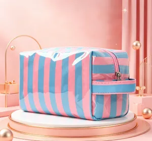 Vue détaillée de la trousse de maquillage en PVC rayé rose et bleu avec poignée latérale.