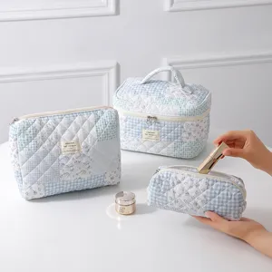 Close-up detail of three blue floral quilted cotton cosmetic bags for travel storage