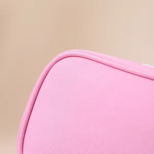 Macro detail of the high-quality pink fabric texture and fine stitching on a makeup bag.