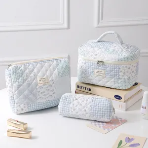 Three-piece quilted cotton floral cosmetic bag set featuring blue and white patchwork patterns