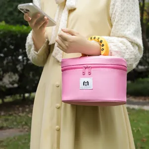 Detail view of a stylish pink cosmetic bag with a unique yellow numbered handle being held