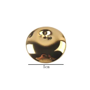 Macro detail of a 5cm polished gold-finished stainless steel circular spring eye brooch