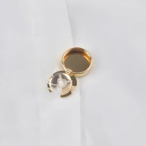 Primer plano de un cubrebotón decorativo de metal dorado en camisa blanca