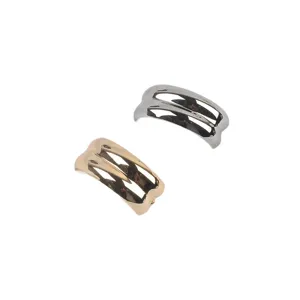 Macro view of two C-shaped wavy metallic brooches in gold and silver finishes