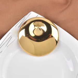 Detailed view of the mirror-like gold finish on a convex circular stainless steel brooch.
