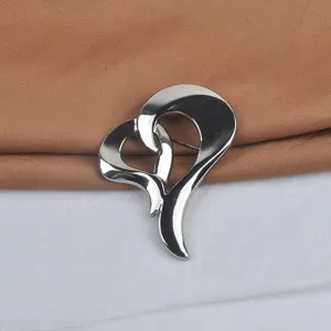 Vista de detalle de un broche de corazón metálico con acabado plateado pulido para traje.